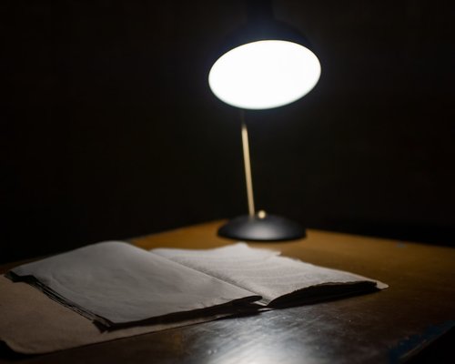 Close up of a warm desk lamp lighting an open book